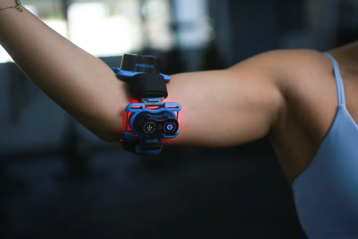 Kineon Move+ device positioned around the elbow during a targeted photobiomodulation session.